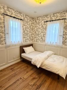 two beds in a room with wallpaper at Maison de L in Hokuto