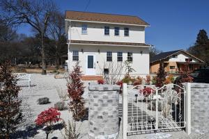 a white house with a gate in front of it at Maison de L in Hokuto
