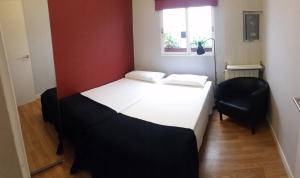 1 dormitorio con 1 cama blanca y 1 silla negra en Piso Playa Patacona/Malvarrosa, en Valencia