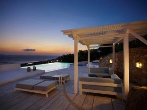 a patio with couches and a pergola next to a pool at Epic Blue Mykonos in Houlakia