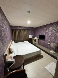 a bedroom with a bed and a table and a tv at 貴族旅社 宜蘭縣旅館095號 in Luodong