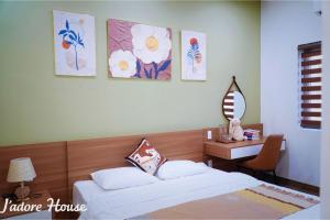 a bedroom with two beds and a desk and paintings on the wall at Jadore House in Danang