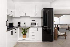 a black refrigerator in a kitchen with white cabinets at Acro Caldo Suites in Akrotiri