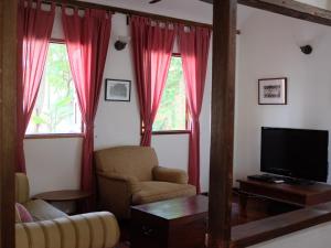 a living room with red curtains and a television at Rumah Jah Langkawi in Pantai Cenang