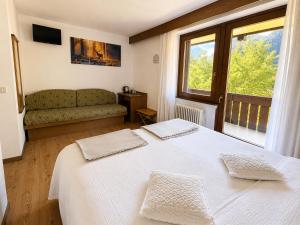 a bedroom with a white bed and a couch at Chalet La Felce in Carisolo