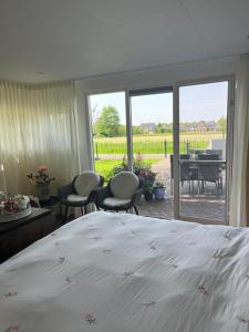 a bedroom with a bed and a view of a garden at De Veldeling in Hollandscheveld