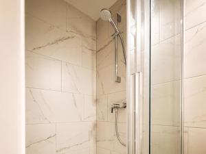 a bathroom with a shower with white marble walls at Spitzen Blicke – Apartments in Silbertal +130 photos