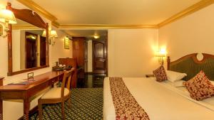 a hotel room with a bed and a desk at Hotel Nahar Nilgiris in Ooty