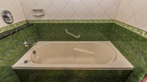 a white bath tub in a green tiled bathroom at Hotel Nahar Nilgiris in Ooty +18 photos