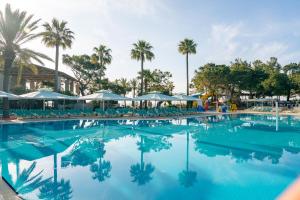 a swimming pool with palm trees and blue water at Pirates Beach Club -Ultra All Inclusive in Tekirova