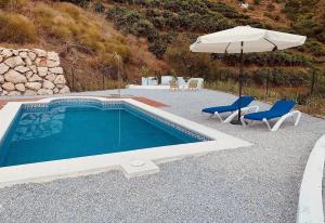 a swimming pool with two chairs and an umbrella at Casa Verdejo in Cómpeta