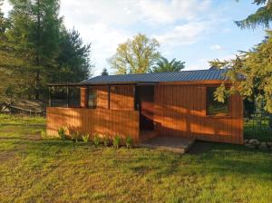 a wooden house with a deck in a field at Zielona Polana in Debrznik