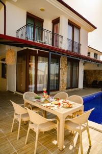 a patio with a table and chairs and a house at Comfy Villa Ipek with Pool in Kaş