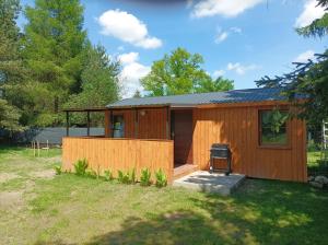 a small wooden cabin with a grill in a yard at Zielona Polana in Debrznik