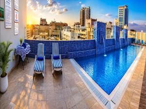 a balcony with two chairs and a large swimming pool at Tulip Hotel Apartments in Dubai