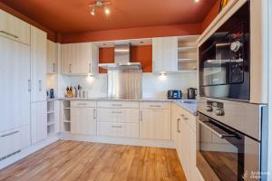 a kitchen with white cabinets and a black microwave at Villa Pal'Ange Hotelservice Playstation 5 Billiard in Durbuy