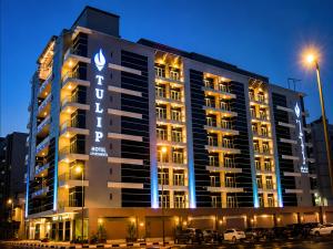a large building with a sign on it at night at Tulip Hotel Apartments in Dubai