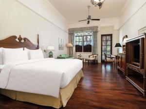 a bedroom with a large white bed and a television at Hotel Majapahit Surabaya MGallery in Surabaya