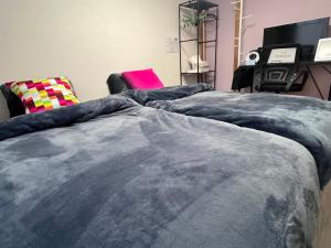 two beds in a room with a chair and a bedspread at Cafe Sharehouse Kokoro Nest Kyoto in Kyoto
