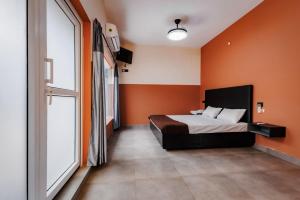 a bedroom with orange walls and a bed and a window at Nitz the loft in Pondicherry