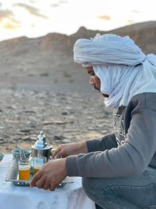 a woman with a turban sitting at a table at Desert mountains camping in Merzouga