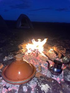 a tea kettle and a tea pot sitting next to a fire at Desert mountains camping in Merzouga