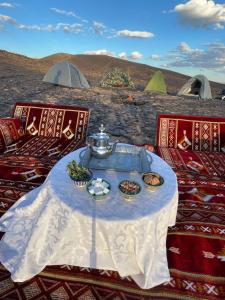 a table with food on it with tents in the background at Desert mountains camping in Merzouga