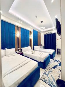 a hotel room with two beds and blue curtains at Hotel G in Sūhāj