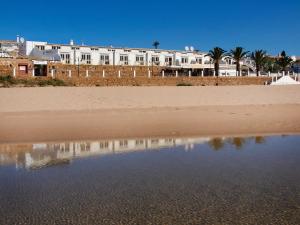 a building on the beach with a reflection in the water at Luz Beach Apartments in Luz