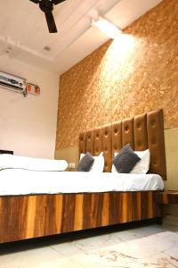 a bedroom with a large bed with a wooden headboard at Hotel Embassy In - 200 Mtrs - Near Golden Temple in Amritsar