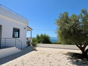 a white house with a fence and a tree at The Izi House in Egina +37 photos