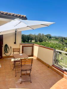 a patio with a table and chairs and an umbrella at AgroVerde Apartment a 10 minuti da Alghero in Tottubella
