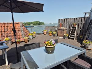 a table on a deck with an umbrella and flowers at All Exclusive Apartments in Dordrecht