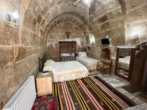 a room with two beds in a stone wall at Karballa Hotel in Aksaray
