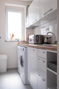 a white kitchen with a washing machine and a sink at Rron's House in Prizren