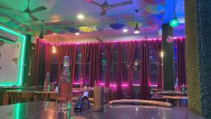 a restaurant with tables and chairs and pink lights at Blue Horizon hotel & restaurent in Nalbāri