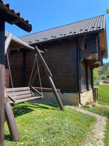 a swing in front of a wooden house at Котедж Славний гуцул & СПА чани джакузі in Yablunytsya