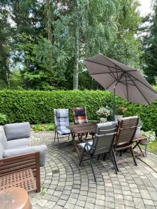 a patio with a table and chairs and an umbrella at Helsinki Hallainvuori yksityismajoitus in Helsinki