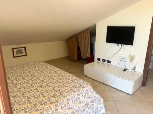 a bedroom with a bed and a flat screen tv at AgroVerde Apartment a 10 minuti da Alghero in Tottubella