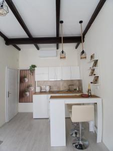 a kitchen with white cabinets and a table and chairs at Studio D lux Vida in Apatin +3 photos