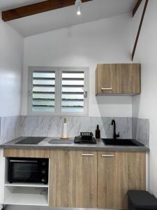 a kitchen with a sink and a microwave at Studio Colibri vue mer in Quartier Morne Acajou