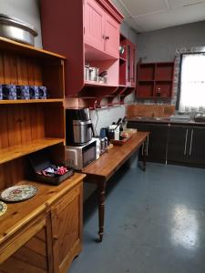 a kitchen with red cabinets and a wooden table with a microwave at De Oude Schuur in Stellenbosch