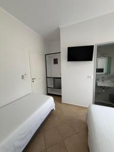 a bedroom with two beds and a tv on the wall at Himara Royal Hotel in Himare