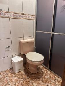 a bathroom with a toilet and a trash can at Casa com Quartos compartilhados in Rio Branco