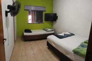 two beds in a room with green walls and a window at Jams Hostel - Pousada perto da Ufcat in Catalão