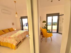 a bedroom with a bed and a yellow chair at The Izi House in Egina