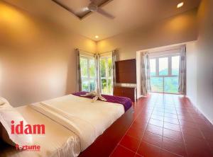 a bedroom with a bed and a large window at Idam Resort in Vagamon