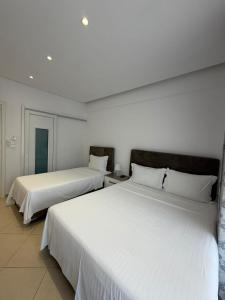 two beds in a hotel room with white sheets at Himara Royal Hotel in Himare