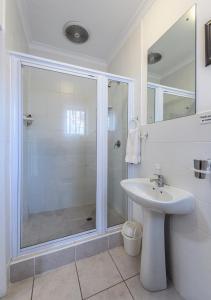 Un baño blanco con ducha y lavabo. en Summer Blue Guesthouse, en Port Elizabeth
