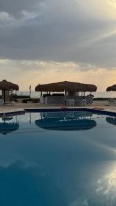 a large swimming pool with a beach and umbrellas at Authentic Cozy Chalet Near the Beach in Ras Sedr